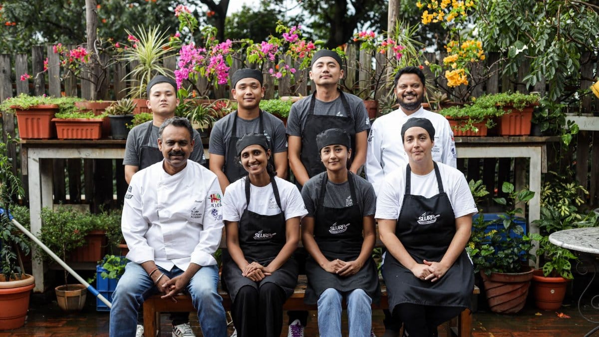 Team of chefs and kitchen staff smiling in a vibrant garden, showcasing unity and professionalism.