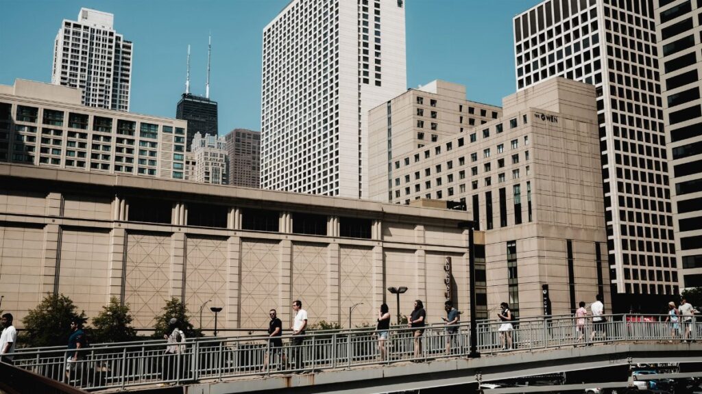 People crossing a bridge with the skyscrapers of Chicago's skyline in the background.