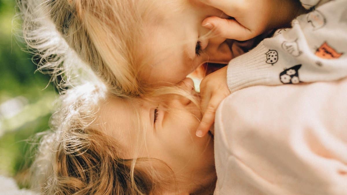 Heartwarming close-up of two blonde children playfully bonding outdoors.