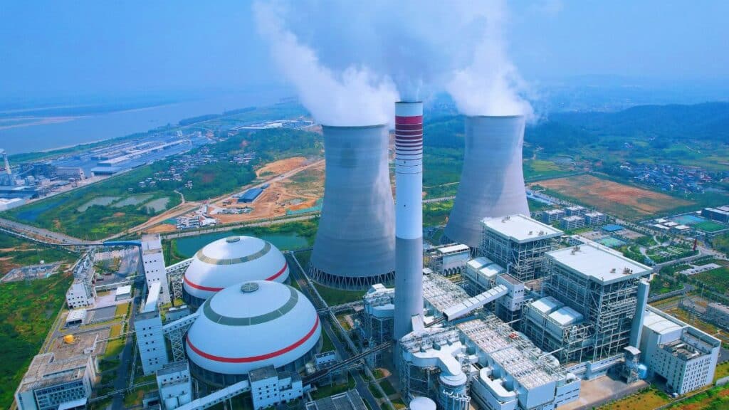 Aerial shot of a power plant with cooling towers emitting steam in Jiujiang, China.