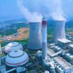 Aerial shot of a power plant with cooling towers emitting steam in Jiujiang, China.