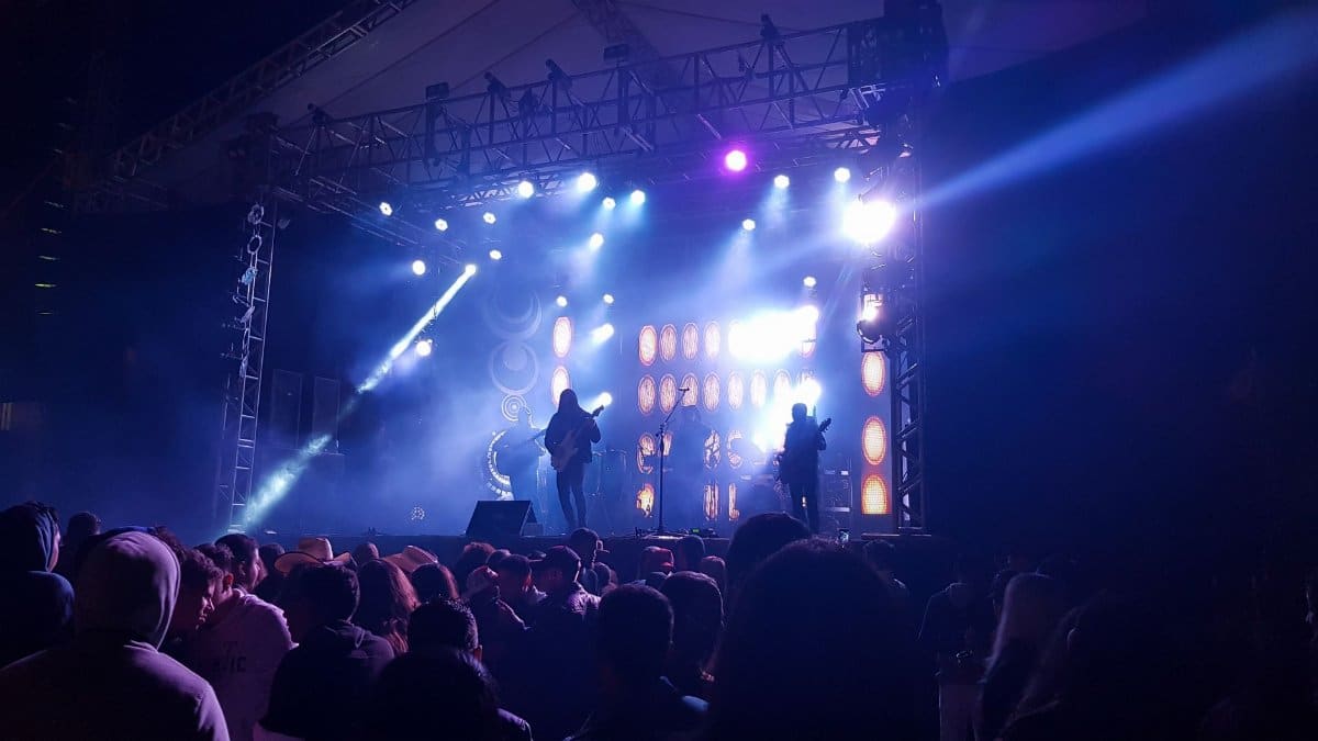 Crowd enjoying a live band performance at a night music festival with colorful stage lights.