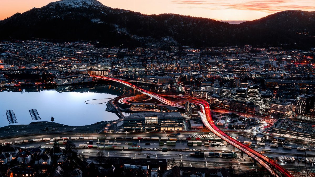 Stunning aerial view of Bergen cityscape with vibrant sunset and city lights reflecting on the water.