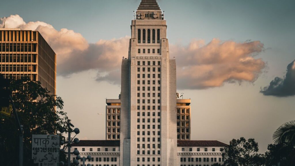 Iconic Los Angeles City Hall illuminated by a dramatic sky at sunset, showcasing urban architecture.