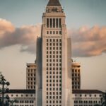 Iconic Los Angeles City Hall illuminated by a dramatic sky at sunset, showcasing urban architecture.