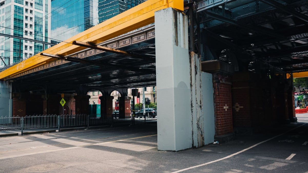 A steel overpass in a modern city landscape, with towering skyscrapers and urban architecture.