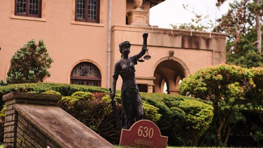 Charming mansion in Arizona City with a Lady Justice statue and manicured garden, perfect for travel and architecture themes.