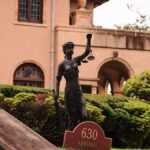 Charming mansion in Arizona City with a Lady Justice statue and manicured garden, perfect for travel and architecture themes.