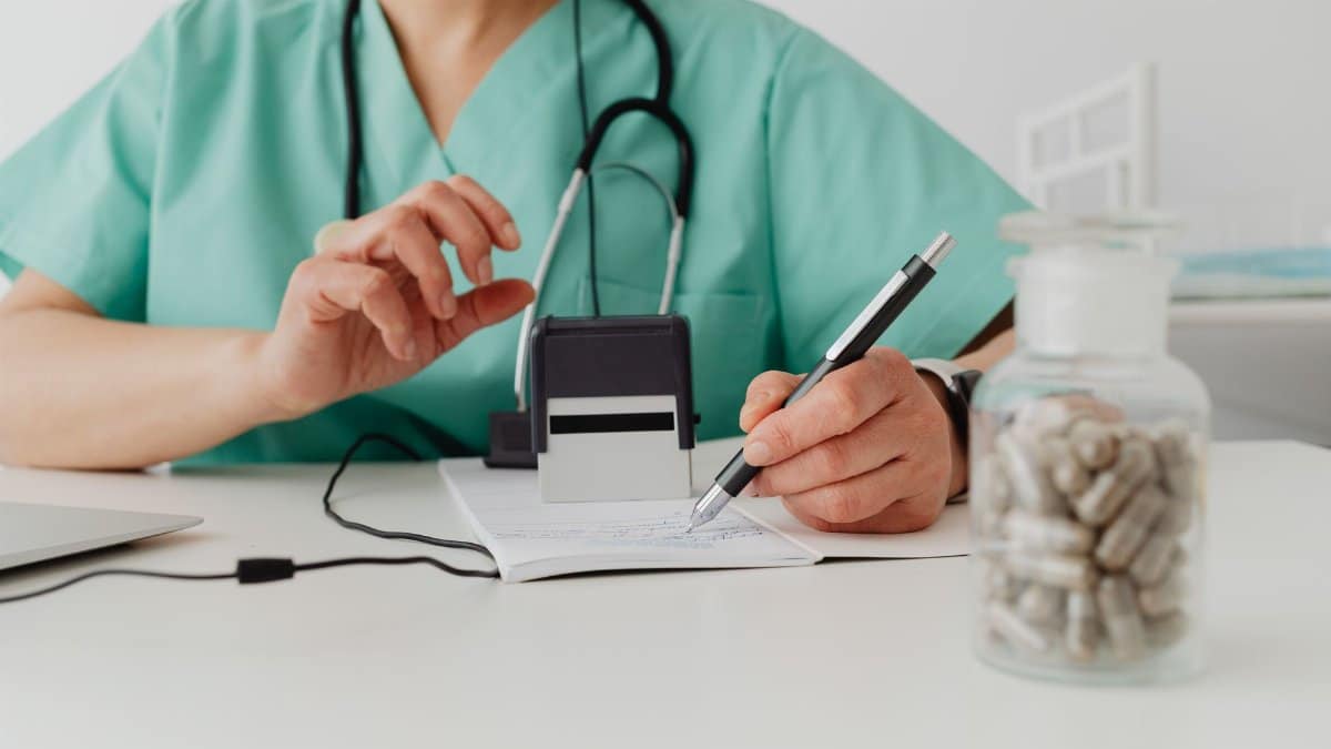 A medical professional writing a prescription in a clinical setting.