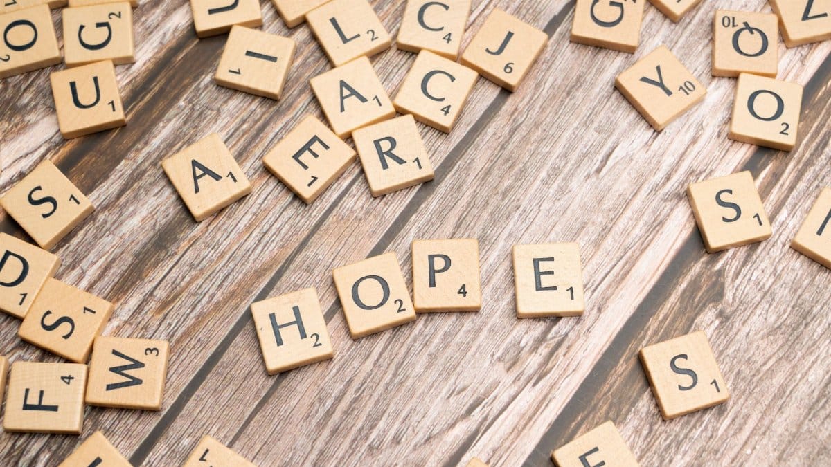 Scrabble tiles spelling 'hope' on a rustic wooden background, symbolizing inspiration.