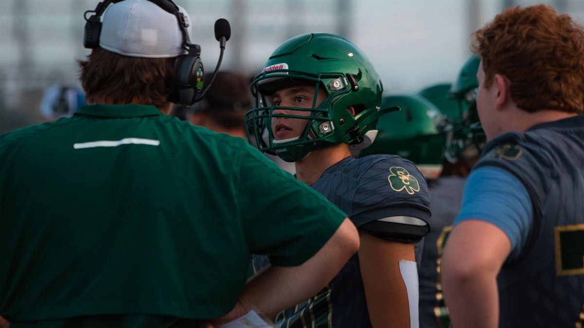 Football players and coach strategize during a game at a stadium.