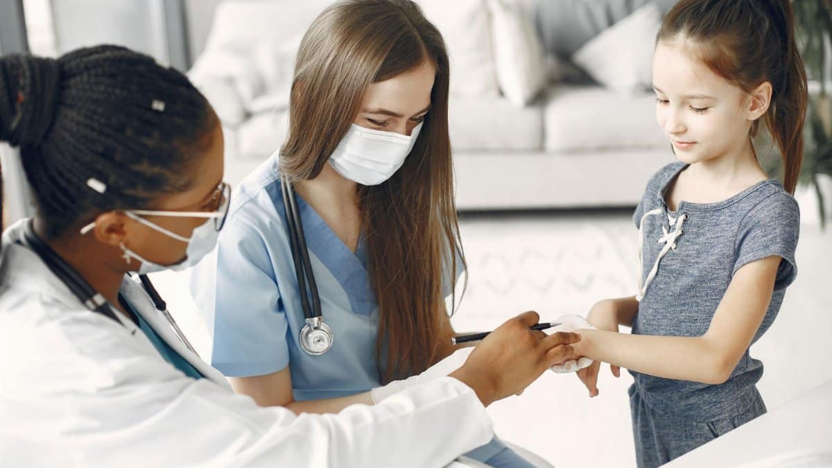 Doctors and a nurse wearing masks attending to a child for a healthcare checkup.