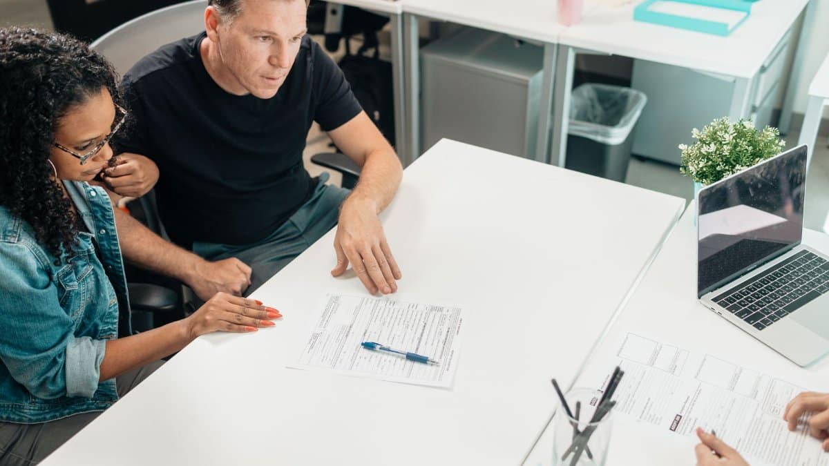 A couple discusses legal documents with a professional in a modern office setting.