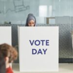 Two women casting their votes in an office during election day, focusing on diversity and civic engagement.