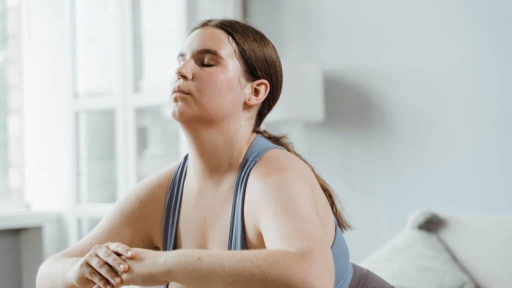 A plus size woman practicing yoga indoors with focus on wellness and relaxation.
