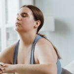 A plus size woman practicing yoga indoors with focus on wellness and relaxation.