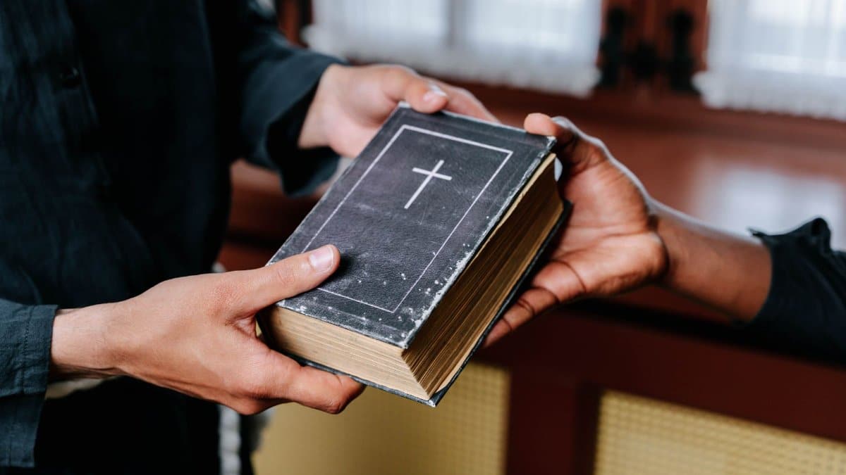 Close-up of hands exchanging a Bible, symbolizing religious connection and faith.