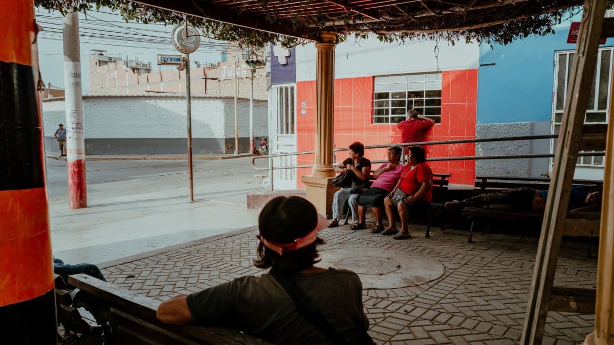 A group of locals relaxing under a shaded area in Pacasmayo, Peru, capturing a typical street scene.