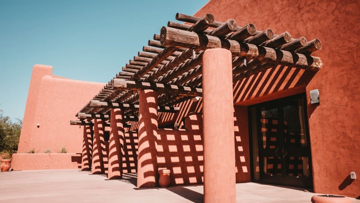 Terracotta building with wooden trellis and shadow pattern in sunny Phoenix, AZ.