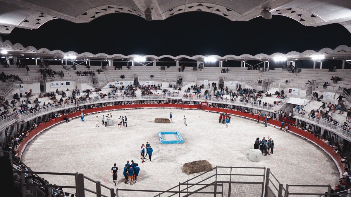 A lively scene at an indoor sports arena filled with spectators and participants at night.