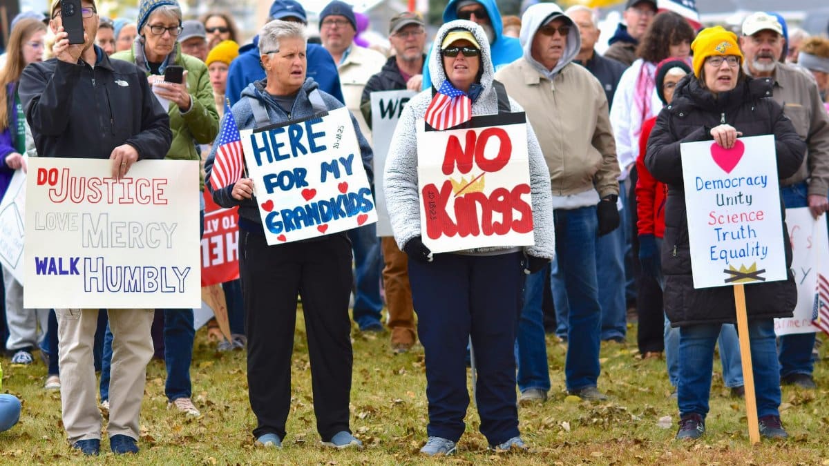 A diverse group gathered outdoors carrying signs for a peaceful protest.