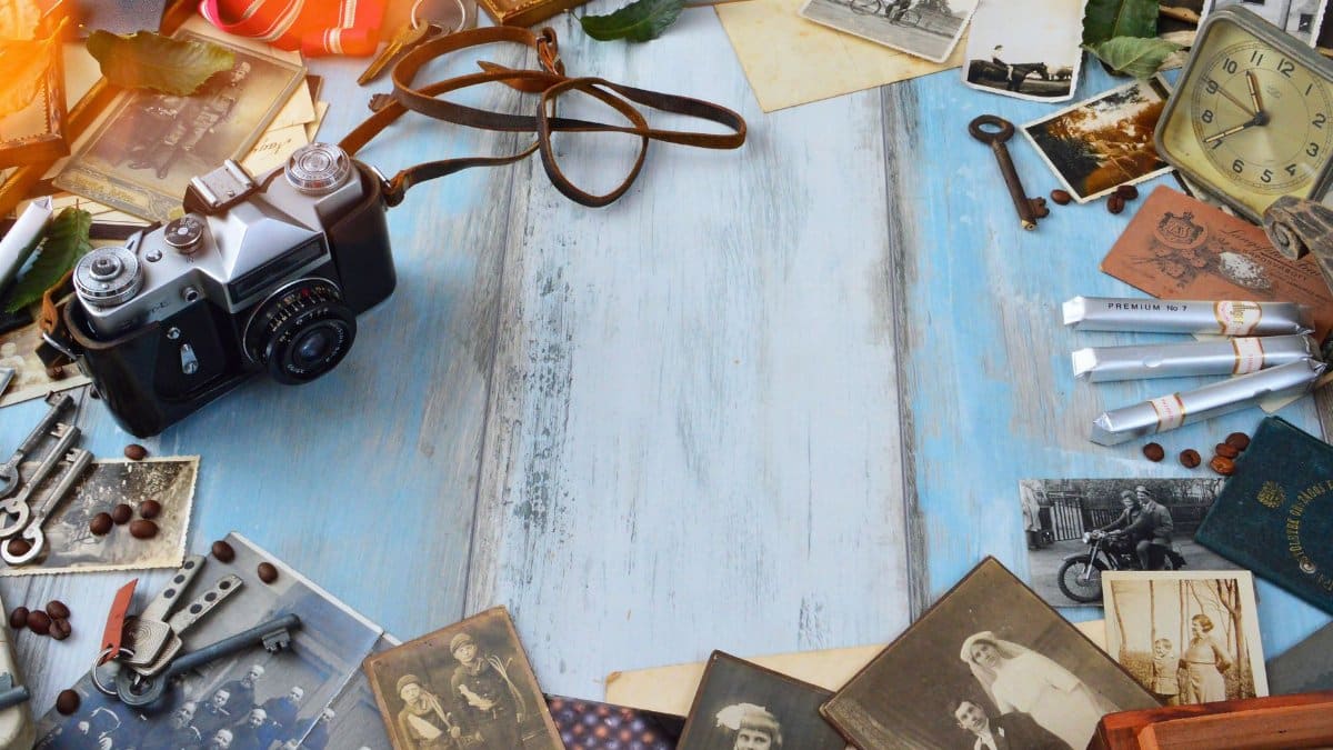 A vintage camera surrounded by nostalgic photos, old keys, and memorabilia on a rustic wooden surface.