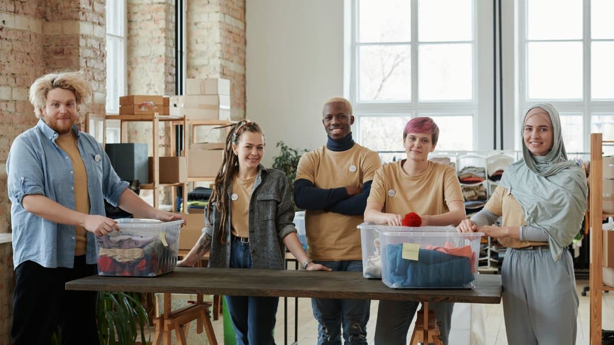 A diverse team of volunteers sorts clothing donations in an organized workspace, promoting community support.