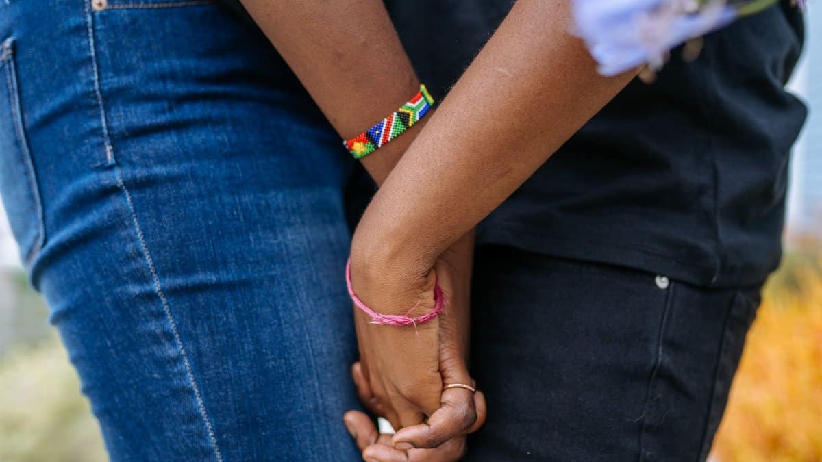 A close-up image of a couple holding hands, showcasing colorful bracelets.
