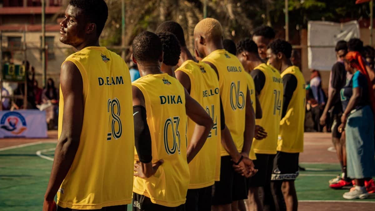 A basketball team stands together on an outdoor court, ready for a game.