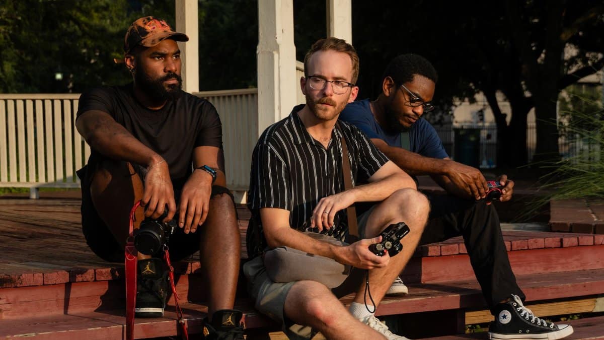 Three friends sitting on steps with cameras on a sunny day in Houston.