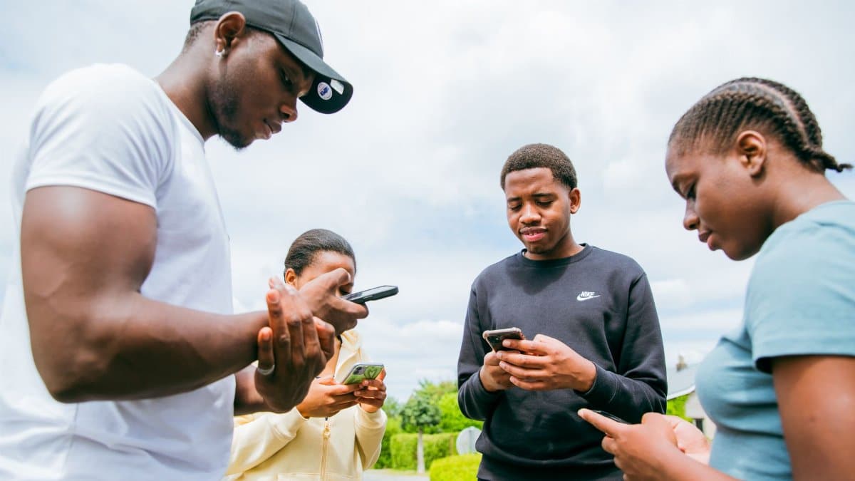 A group of friends engaging with smartphones outside on a bright day in Brussels.