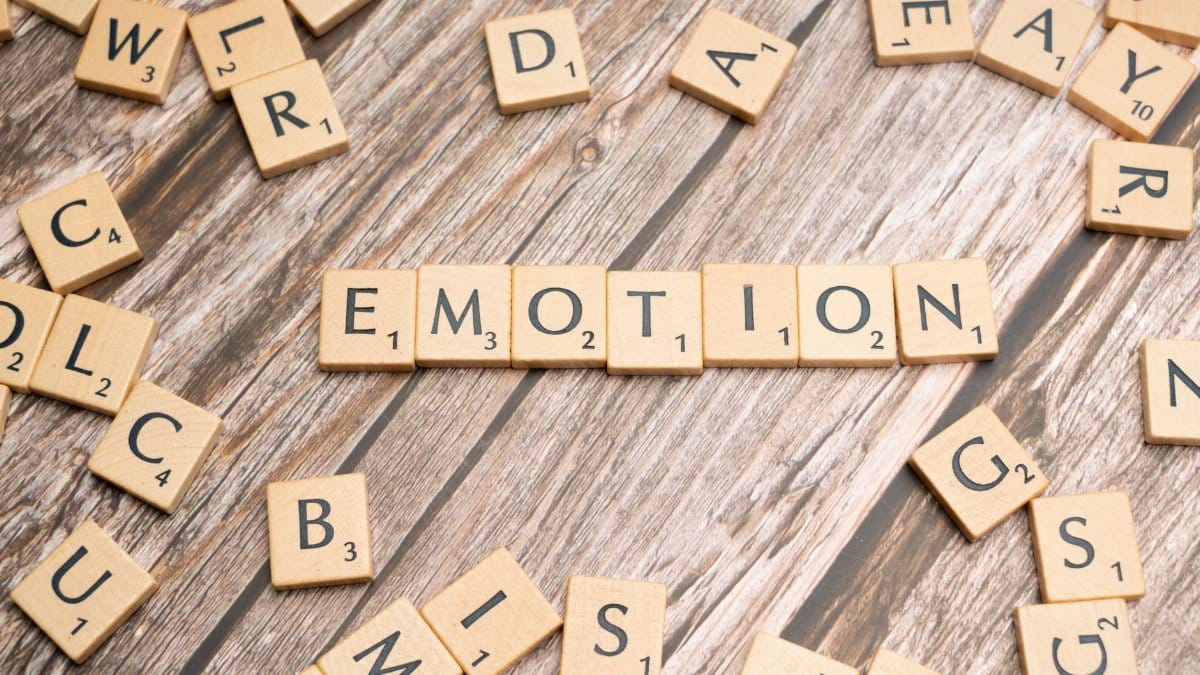 Scrabble tiles forming the word emotion on a wooden background.