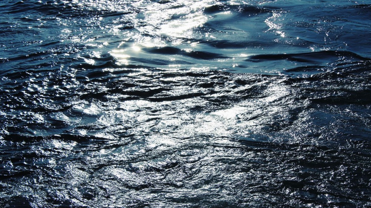 Close-up of a sparkling ocean surface with sunlight reflecting off the waves, creating a shimmering texture.