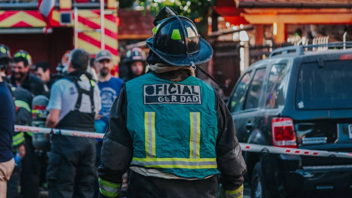 Firefighters gathered on a city street, working collaboratively in an emergency response situation.