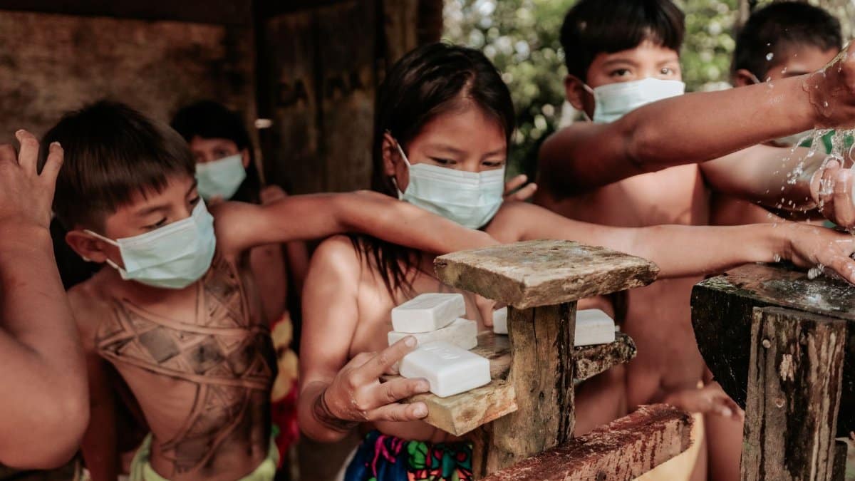 Group of children with face masks using soap and water, promoting hygiene.