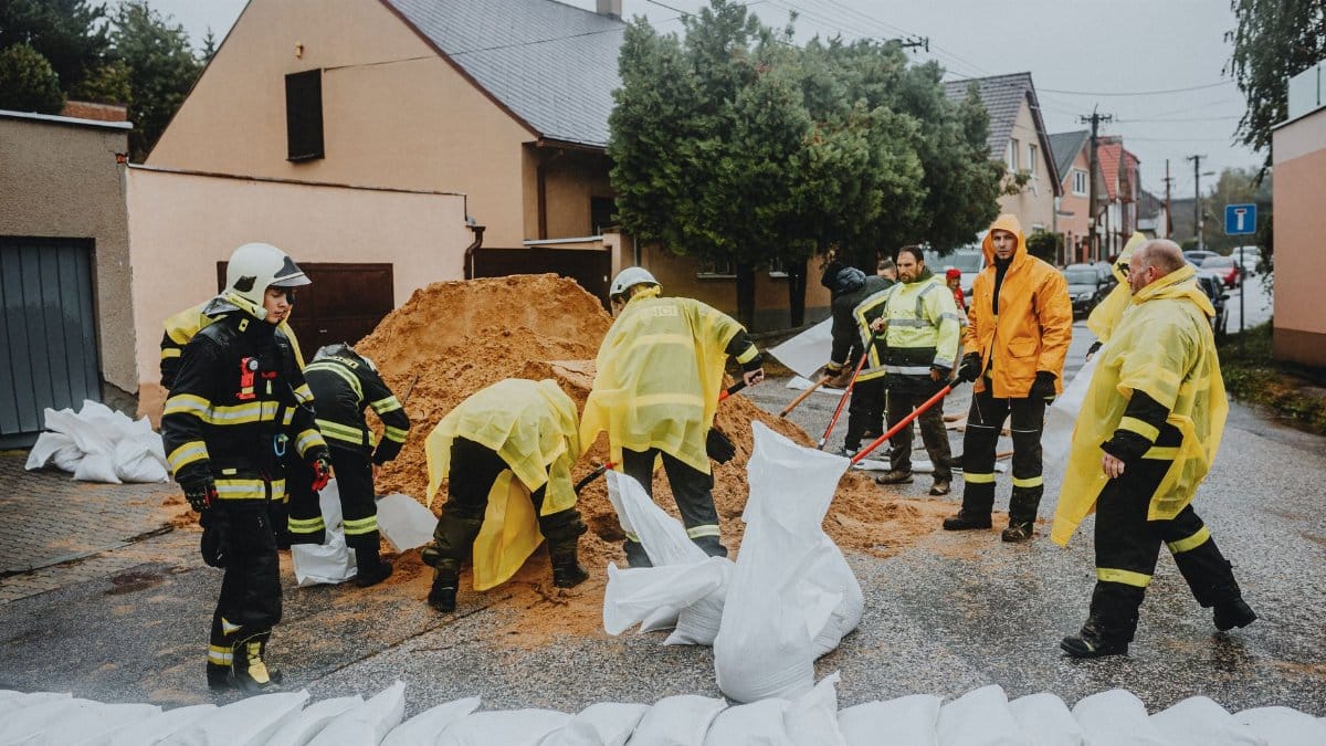 Emergency response team filling sandbags on a rainy street to prevent flooding.