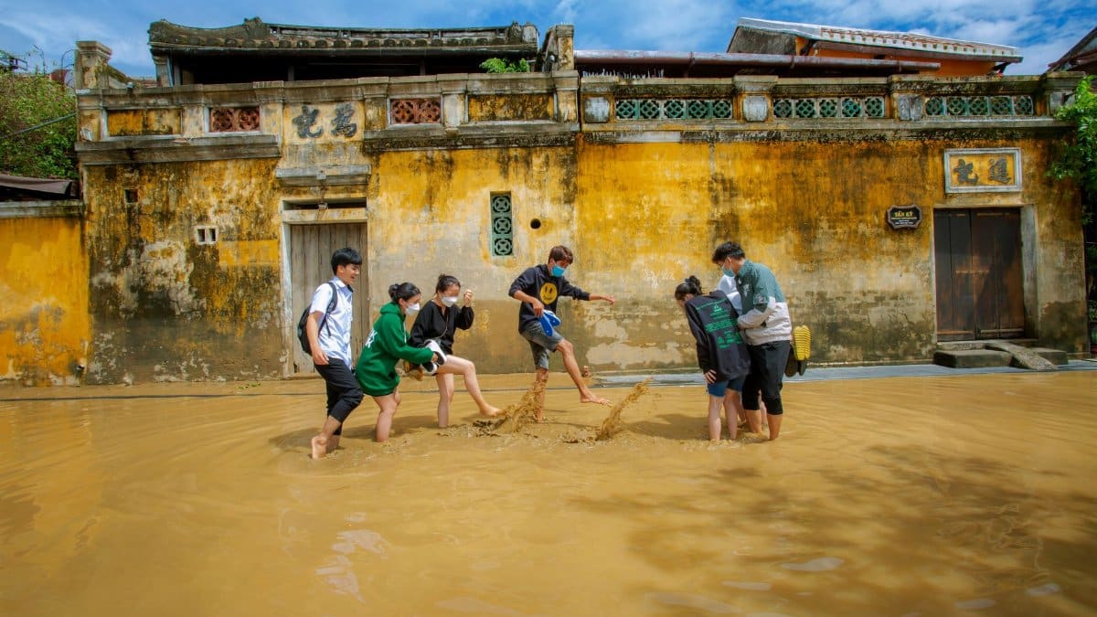 Six young individuals walk through a flooded street in Hoi An, showing resilience and togetherness.