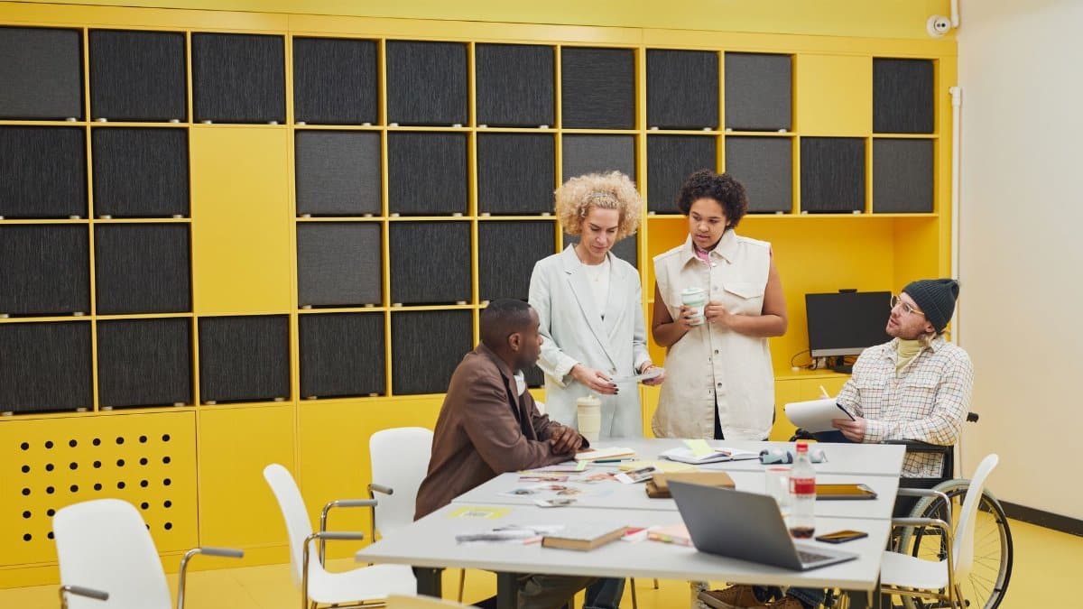 A diverse group of coworkers collaborating in an open-plan office with modern yellow decor.