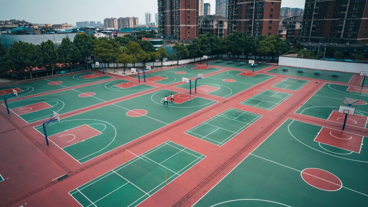 Aerial shot of multiple basketball courts in a residential area of Jiujiang, surrounded by skyscrapers.