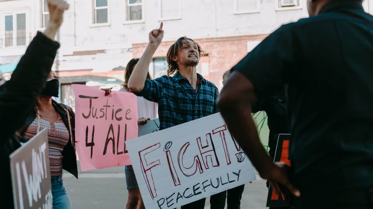 Protesters holding signs for justice and peace during a daytime demonstration outdoors.