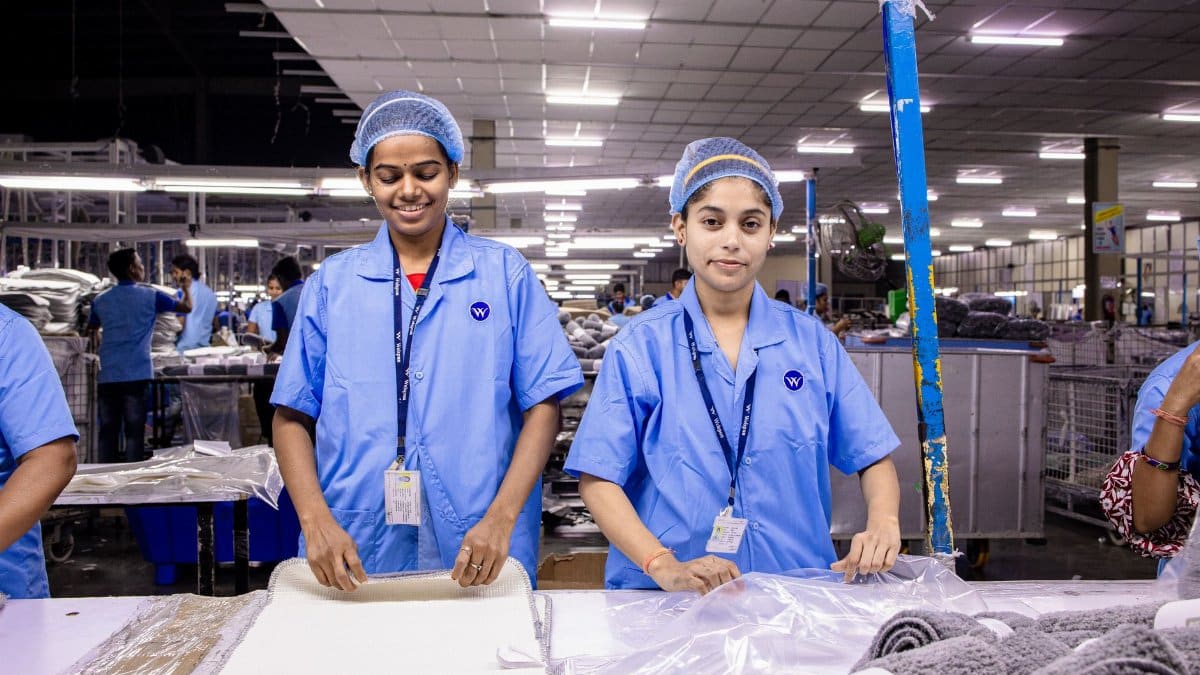 Female workers in uniform assembling fabrics in a modern textile factory setting.