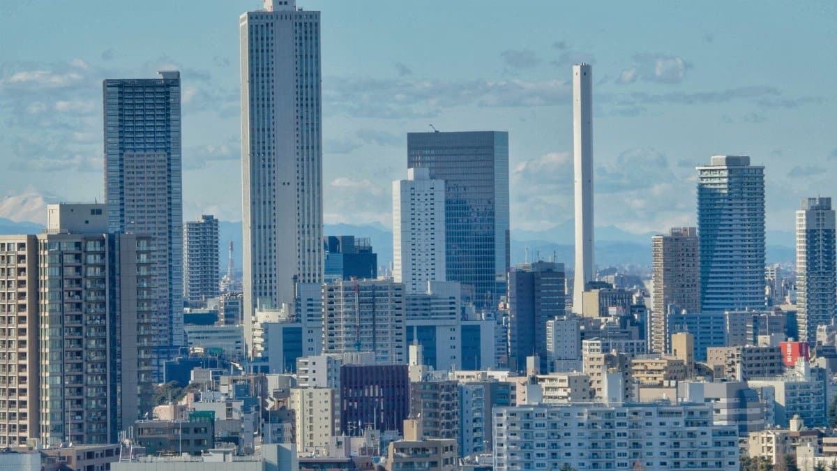 Aerial view of Tokyo's urban skyline with modern skyscrapers against a blue sky.