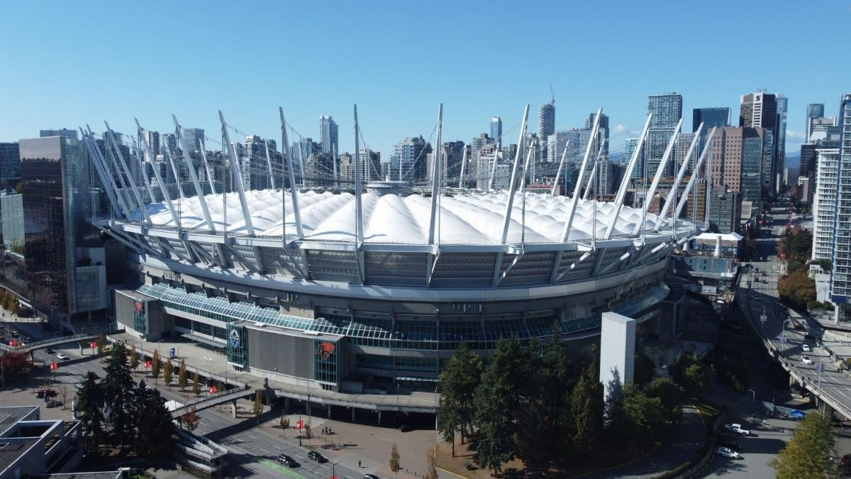Aerial shot of BC Place Stadium in Vancouver with a cityscape backdrop, showcasing modern architecture.