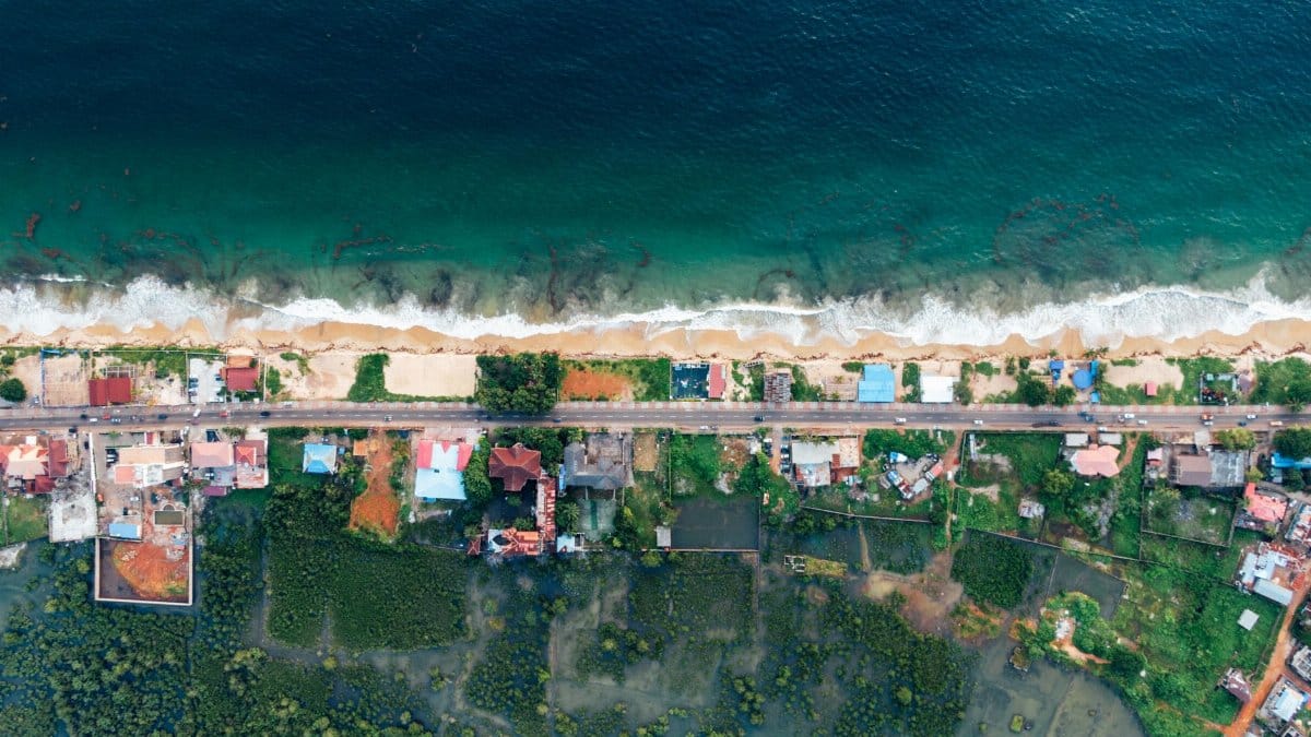 Stunning aerial shot showing a coastal town with waves crashing on the shore.