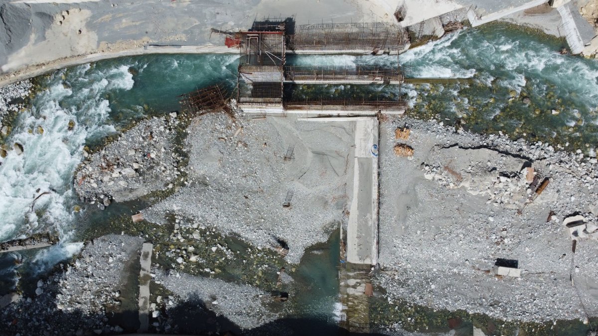 Aerial view of a construction site with a river in Matiltan, Pakistan, showcasing industrial development.