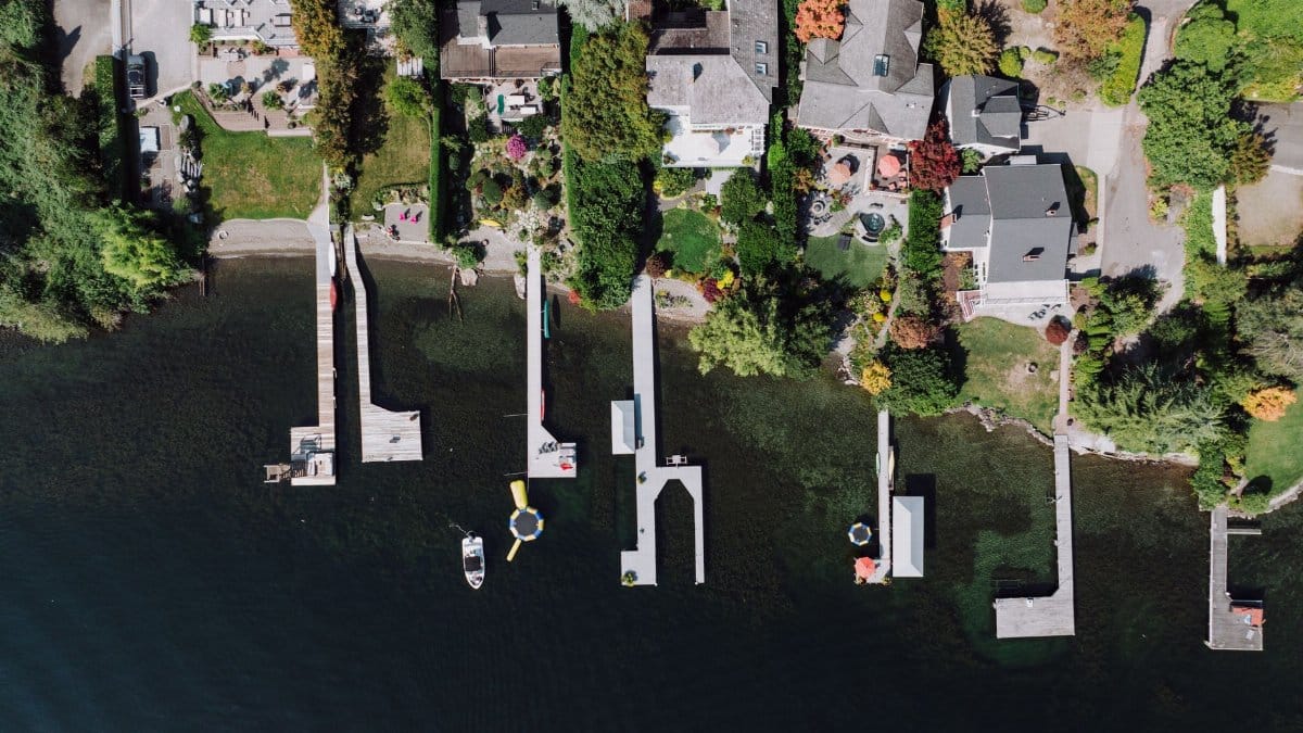 Aerial shot of waterfront homes and piers in Seattle, showcasing lush greenery and serene waters.