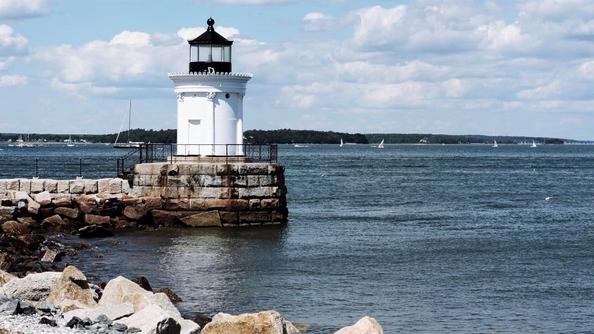 A picturesque lighthouse in Maine overlooking the ocean on a sunny day.