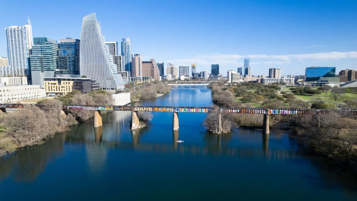 Stunning aerial view of Austin, Texas skyline featuring a graffiti-covered bridge over the river.