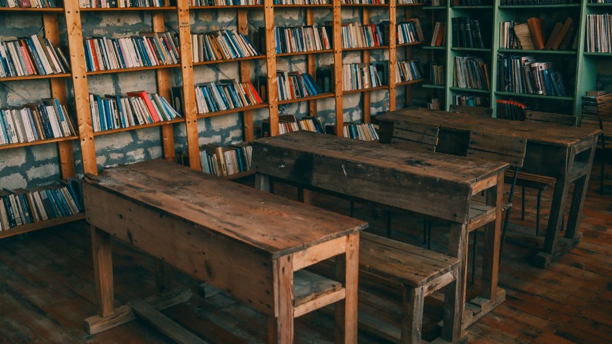Rustic classroom featuring wooden desks and bookshelves filled with books.