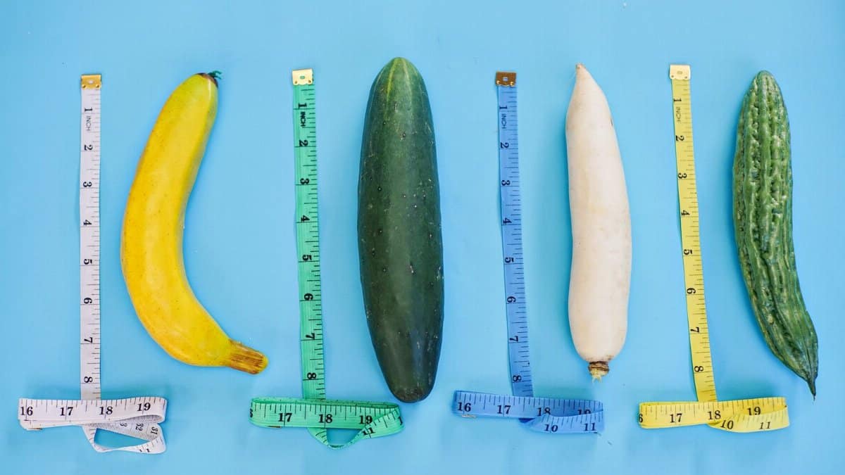 A vibrant still life of various vegetables and measuring tapes on a blue backdrop.